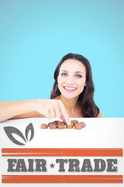 Composite image of pretty brunette picking out chocolate — Stock fotografie