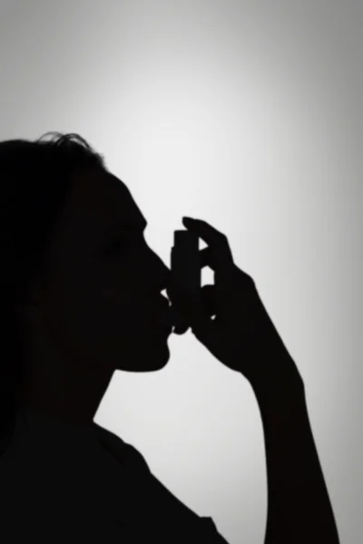 Astmatiska brunett med sin inhalator — Stockfoto