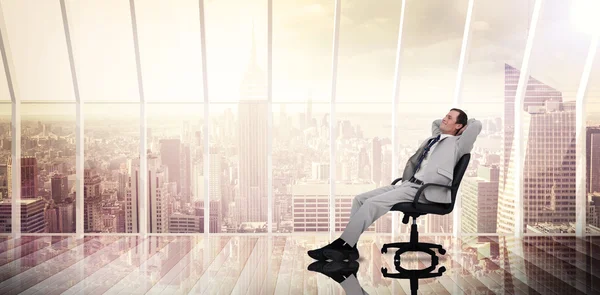 Composite image of businessman relaxing in swivel chair — Stock Photo, Image