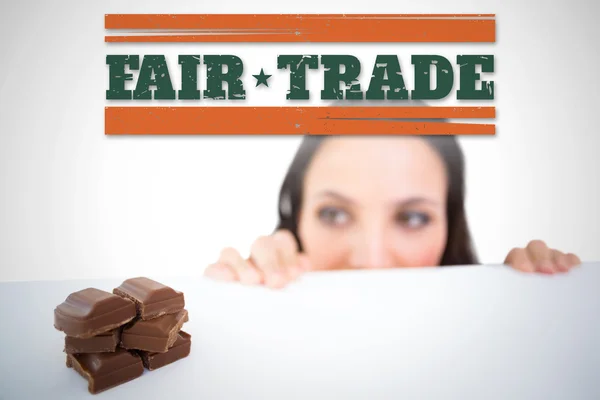 Composite image of pretty brunette peeking at chocolate — Stock Photo, Image