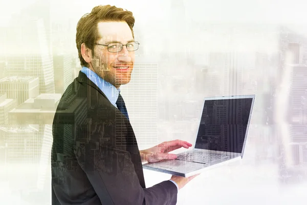 Composite image of smiling businessman using a laptop — Stock Photo, Image