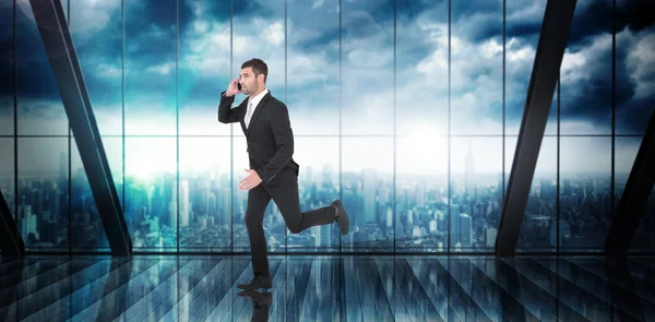 Composite image of businessman running on the phone — 图库照片