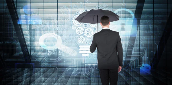Businessman sheltering under black umbrella — Stock Photo, Image