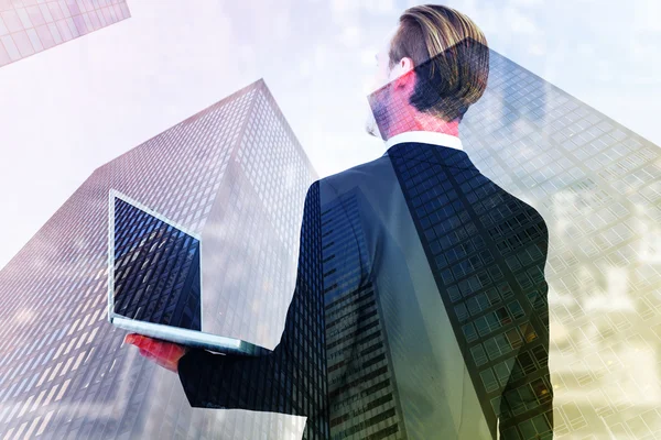 Imagen compuesta del hombre de negocios mirando hacia arriba la celebración de la computadora portátil —  Fotos de Stock