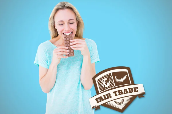 Composite image of happy blonde eating bar of chocolate — Stockfoto