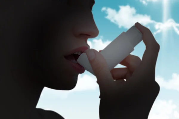 Composite image of blonde woman taking her inhaler — ストック写真