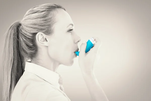 Imagen compuesta de una guapa rubia usando un inhalador de asma — Foto de Stock