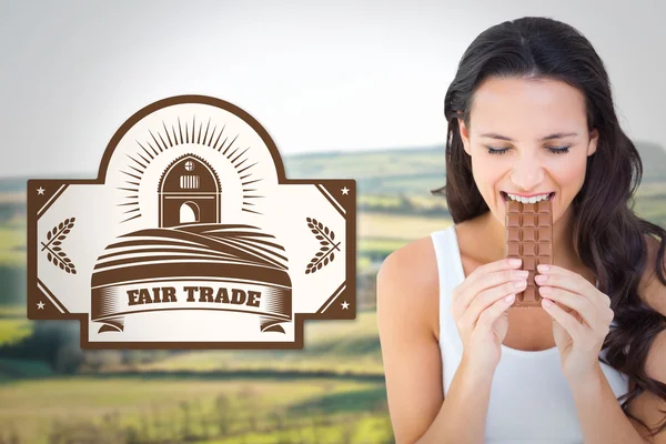Composite image of pretty brunette eating bar of chocolate — Zdjęcie stockowe