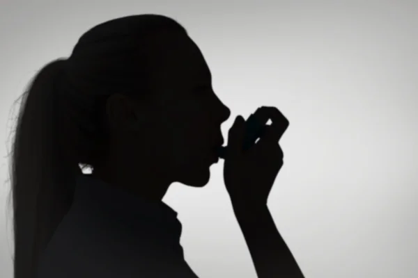 Composite image of pretty blonde using an asthma inhaler — Zdjęcie stockowe