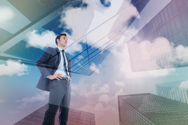 Composite image of serious businessman with hands on hips — Stock Photo, Image