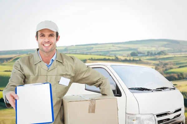 Happy delivery man with box showing clipboard — Stock Photo, Image