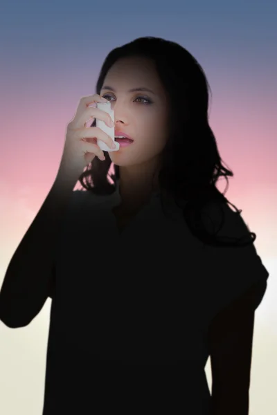 Composite image of asthmatic brunette using her inhaler — Stock fotografie