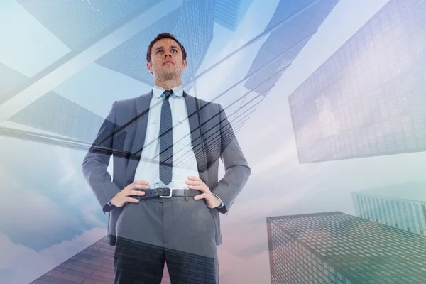 Composite image of serious businessman with hands on hips — Stock Photo, Image