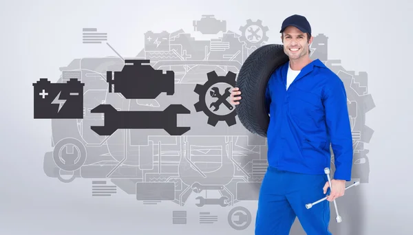 Confident mechanic carrying tire — Stock Photo, Image