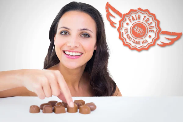 Composite image of pretty brunette picking out chocolate — Stok fotoğraf