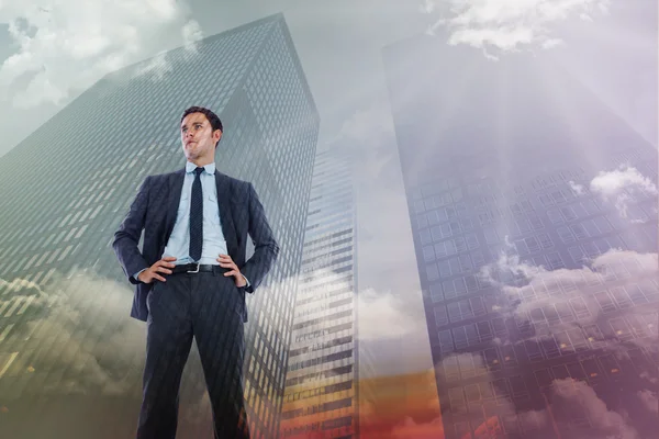 Composite image of serious businessman with hands on hips — Stock Photo, Image