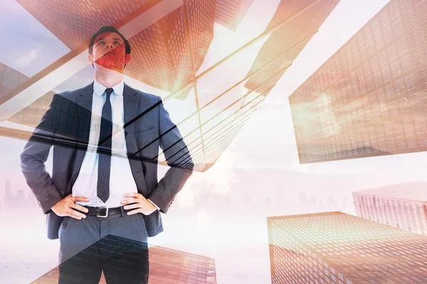 Composite image of serious businessman with hands on hips — Stock Photo, Image