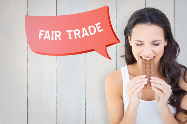 Composite image of pretty brunette eating bar of chocolate — Stock fotografie