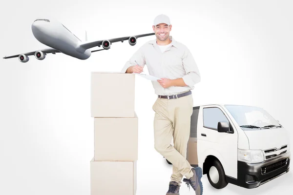 Delivery man with clipboard leaning on cardboard — Stockfoto
