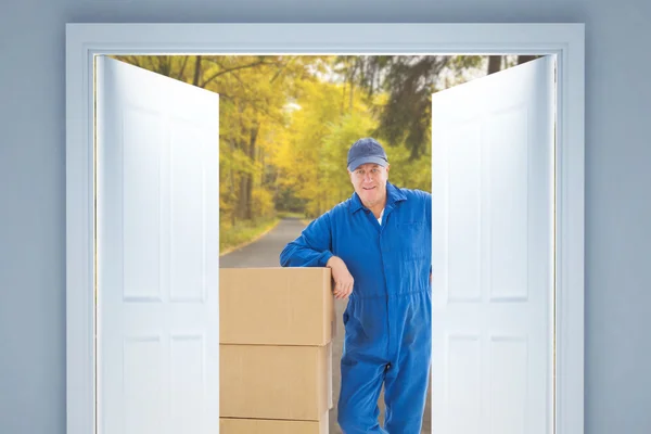 Happy delivery man leaning on pile — Stok fotoğraf