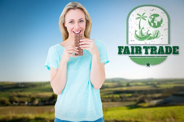 Smiling blonde eating bar of chocolate — Stock Photo, Image