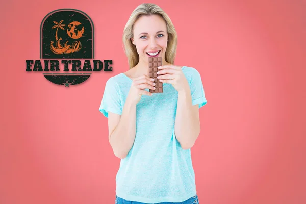 Smiling blonde eating bar of chocolate — Stock Photo, Image