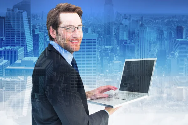 Composite image of smiling businessman using a laptop — Stock Photo, Image