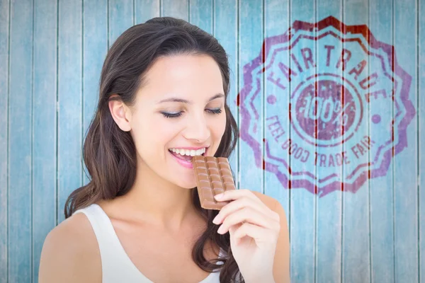 Imagen compuesta de la bonita morena comiendo barra de chocolate —  Fotos de Stock