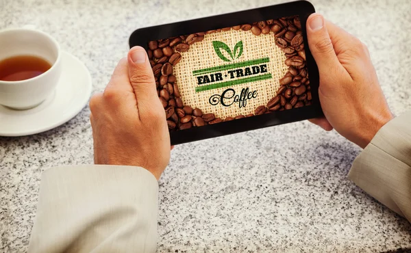 Composite image of businessman holding small tablet at table — Stock Photo, Image