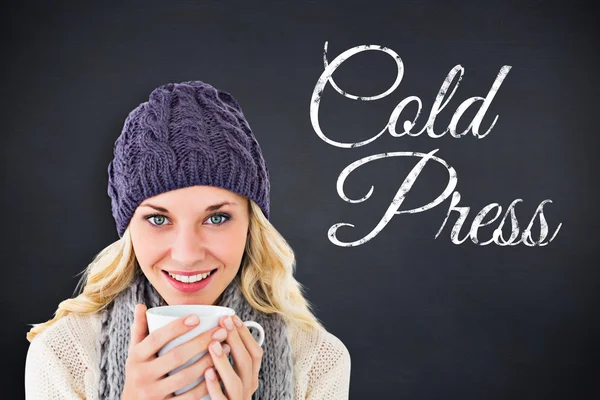 Composite image of pretty blonde in winter fashion holding mug — Stock Photo, Image