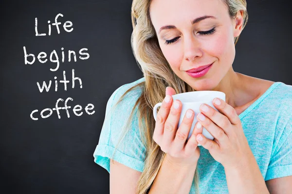 Composite image of smiling blonde with hot beverage relaxing — Stock Photo, Image