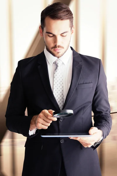 Businessman using magnifying glass — Stok fotoğraf