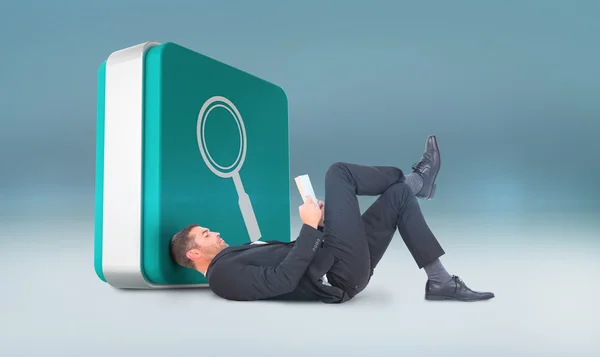 Businessman lying on floor reading book — Stock Photo, Image