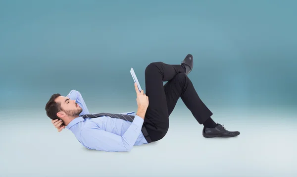 Businessman lying on floor using tablet — Stock Photo, Image