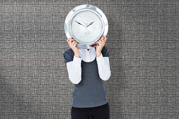Composite image of woman holding clock in front of her head — Stock Photo, Image