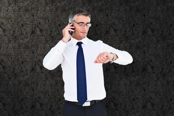 Samengestelde afbeelding van zakenman aan de telefoon kijken naar zijn pols — Stockfoto