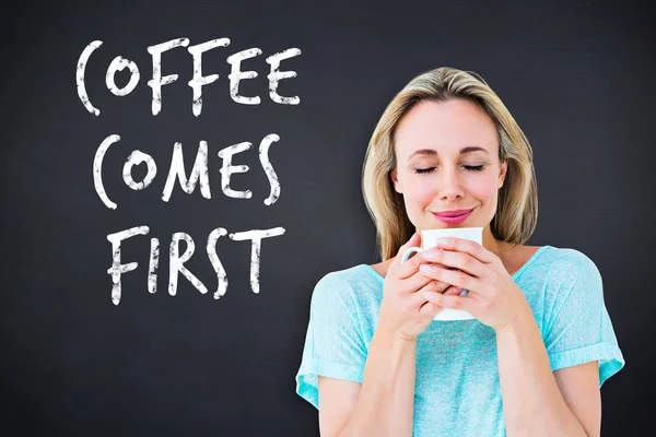 Composite image of cheerful blonde holding mug of hot drinking — Stock Photo, Image