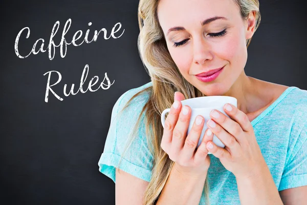 Composite image of smiling blonde with hot beverage relaxing — Stock Photo, Image