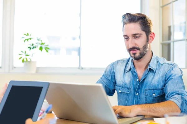 Partners working at desk using laptop and tablet — Stockfoto