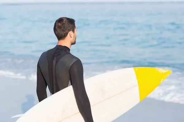 Uomo in muta con tavola da surf in spiaggia — Foto Stock