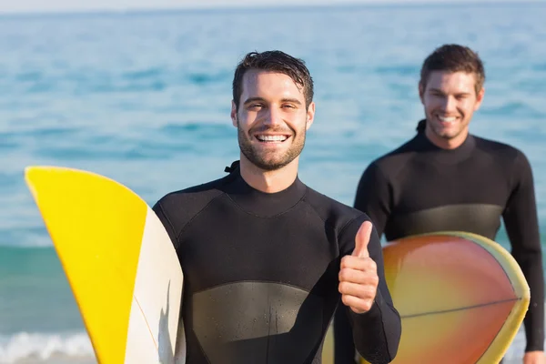 Hombres en trajes de neopreno con tabla de surf en la playa — Foto de Stock