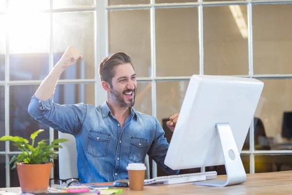 Casual businessman cheering in front of his computer — Stock Photo, Image