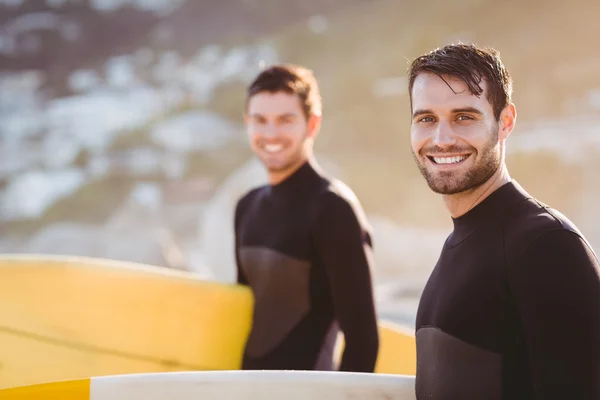 Homens de fato de mergulho com prancha de surf na praia — Fotografia de Stock