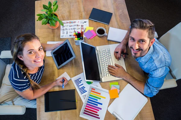 Smiling partners working at desk using laptop and tablet — Zdjęcie stockowe