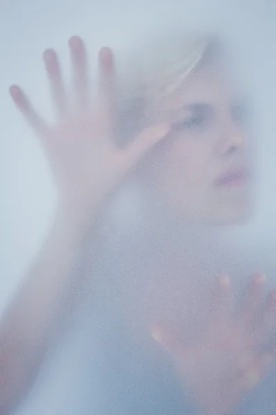 Blond kobieta dotykając szkło matowe — Zdjęcie stockowe