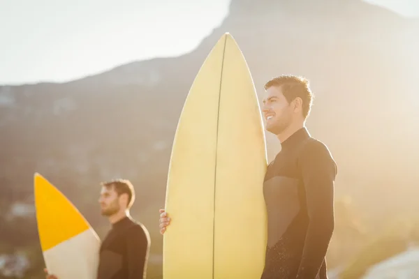 Мужчины в гидрокостюмах с доской для серфинга на пляже — стоковое фото