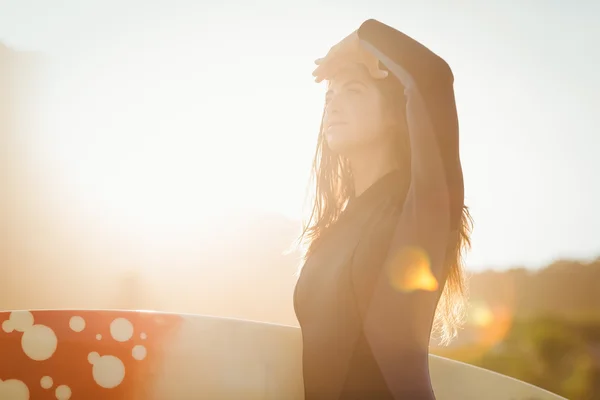 Frau im Neoprenanzug mit Surfbrett am Strand — Stockfoto