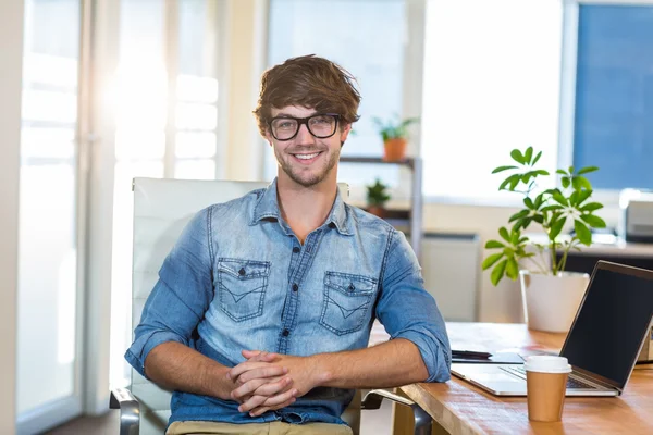 Smiling casual businessman sitting at desk — Stock Photo, Image