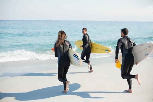 Friends on wetsuits with surfboard at beach — Stock Photo, Image