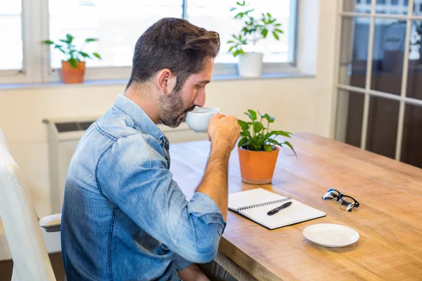 Man sitting at his desk and drinking coffee — Stockfoto